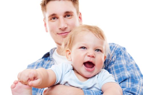 smiley man holding laughing baby boy over white background
