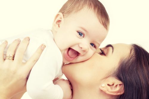 family, child and parenthood concept – happy mother kissing smiling baby