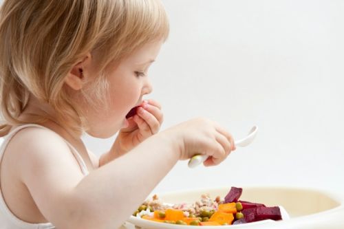 Adorable baby girl eating fresh vegetables