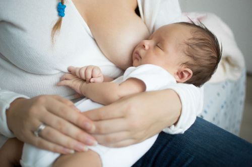 Closeup photo of cute baby sleeping on mothers hands after eating milk