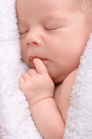 Cute newborn sleeps wrapped in white blanket