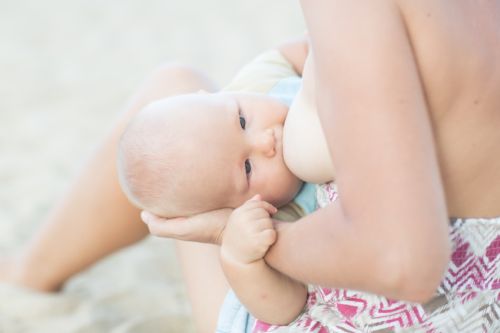 Mother breastfeeding baby on the beach
