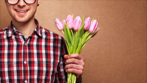 man clothing hipster holding a bouquet of flowers for Valentine’s Day concept, mothers day, birthday.